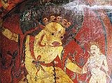 Tibet Guge 08 Tsaparang 05 Yamantaka Temple Yama To the right of the door is a painting of Yama (Tib. Shinje) riding a blue water buffalo. Yama is nude, has a buffalo head, wears a garland of human skulls, has an ornament shaped like a wheel on his breast, his right hand holds a sword topped with a skull, and his left hand holds a loop of rope. On the right is the fierce Dakini Simhaumukha. Snarling and roaring with a gaping large mouth on a white lion face, she stands fierce and menacing with two hands, with protruding fangs, curled tongue, two large round eyes and dark flowing hair. Her left hand clutches to the heart a white skullcup filled with blood. Photo - Thni: Westtibet.